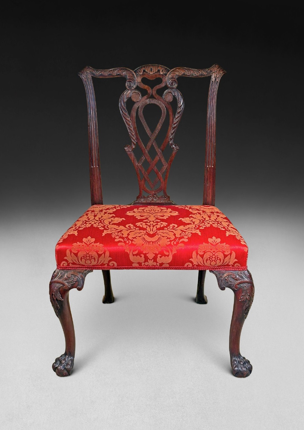 A pair of carved mahogany Chippendale style side chairs with pierced splats, cabriole legs, and red patterned damask upholstered seats. View V
