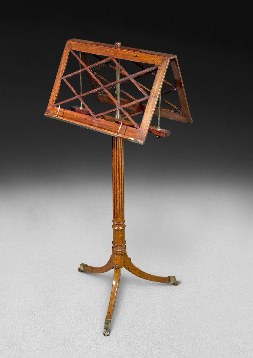 A Regency mahogany duet music stand with a double-sided lattice desk, adjustable brass stem, reeded column, and tripod base. View III
