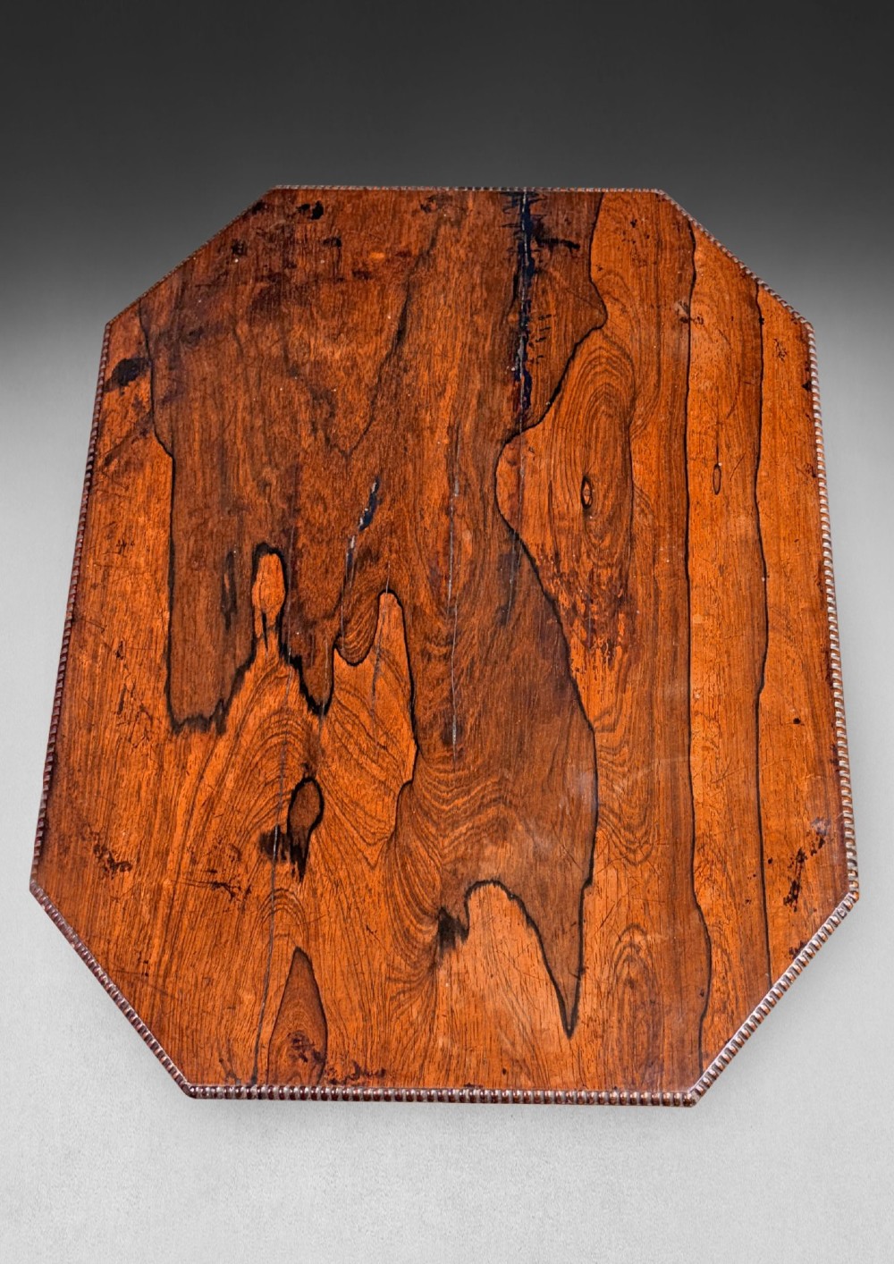 An antique Regency rosewood octagonal wine table with a faceted central column and a carved quadform base. View II