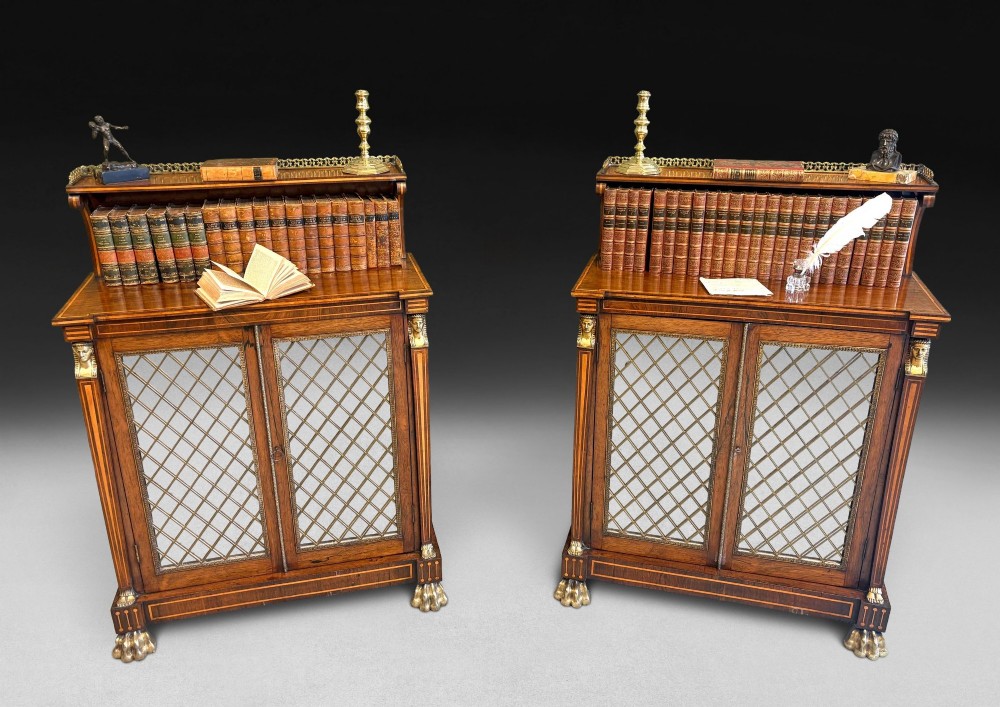 A pair of Regency rosewood chiffoniers featuring boxwood stringing, brass lattice panel doors, upper display shelves with brass galleries, and claw feet.