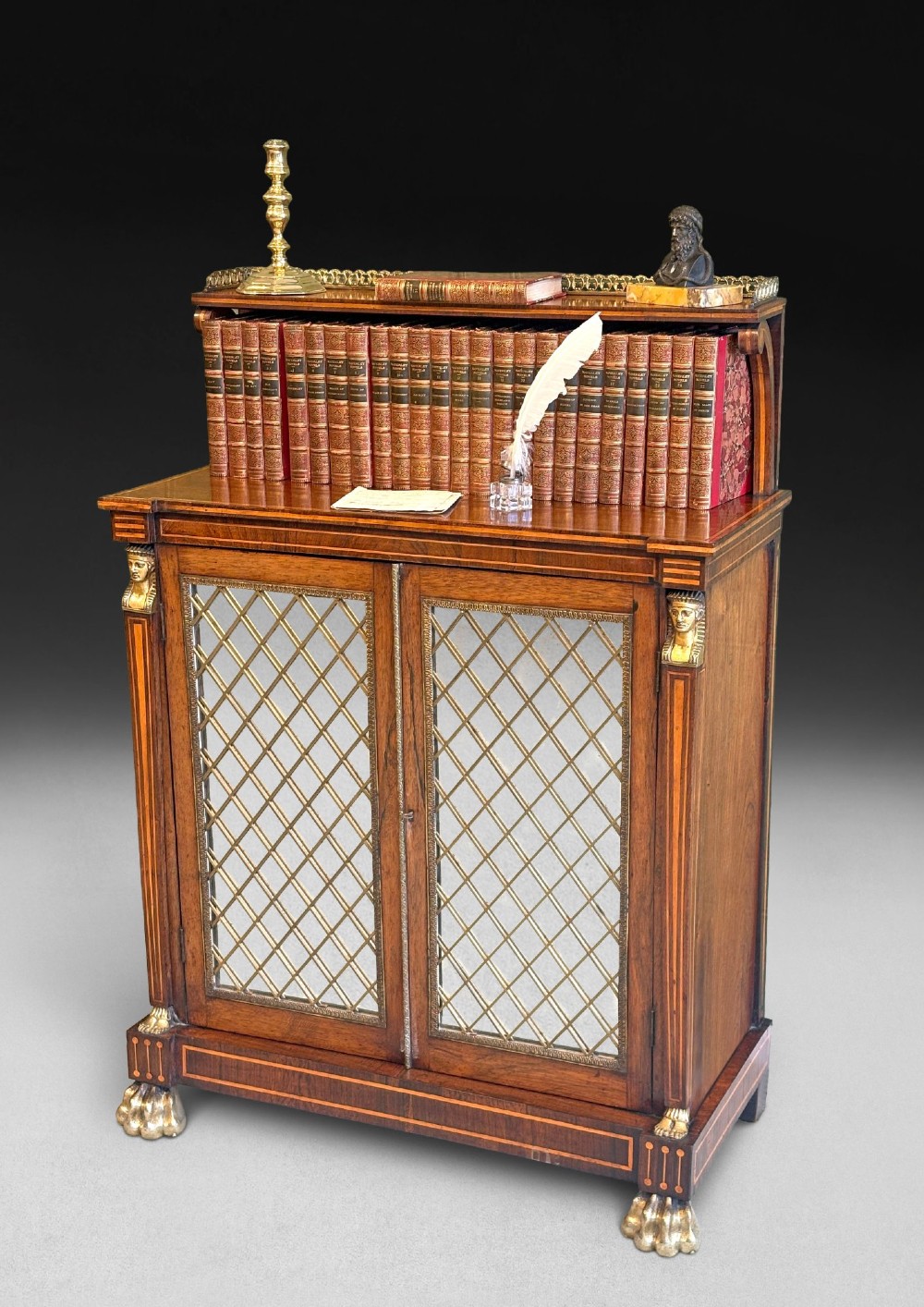 A pair of Regency rosewood chiffoniers featuring boxwood stringing, brass lattice panel doors, upper display shelves with brass galleries, and claw feet. View VI