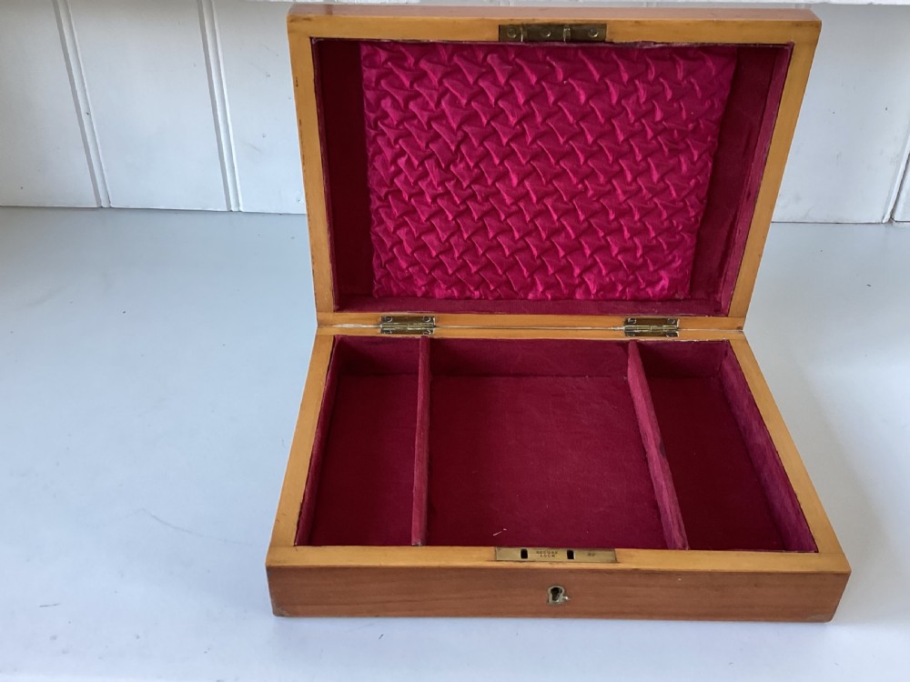 A rectangular mahogany jewellery box with a fitted lid, featuring an inlaid brass shield on top and a central brass keyhole on the front casing. View II