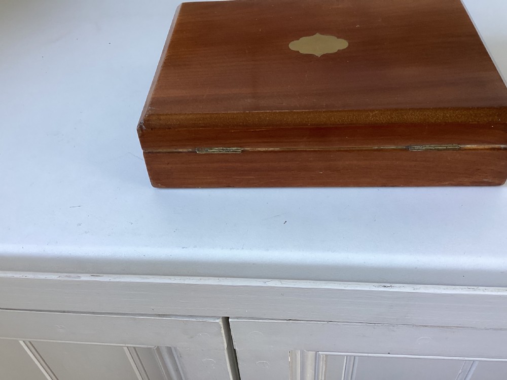 A rectangular mahogany jewellery box with a fitted lid, featuring an inlaid brass shield on top and a central brass keyhole on the front casing. View III