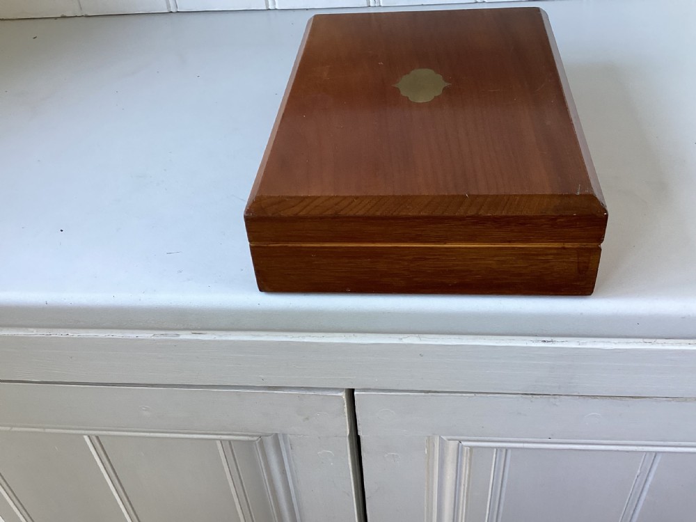 A rectangular mahogany jewellery box with a fitted lid, featuring an inlaid brass shield on top and a central brass keyhole on the front casing. View IV