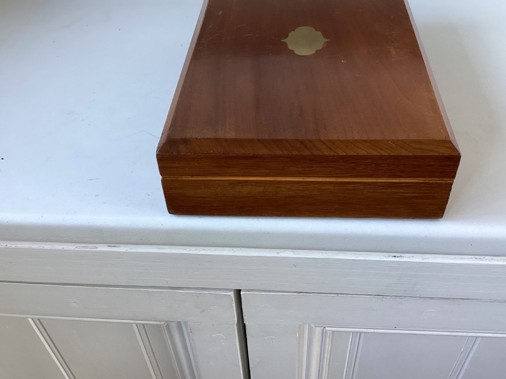 A rectangular mahogany jewellery box with a fitted lid, featuring an inlaid brass shield on top and a central brass keyhole on the front casing. View V