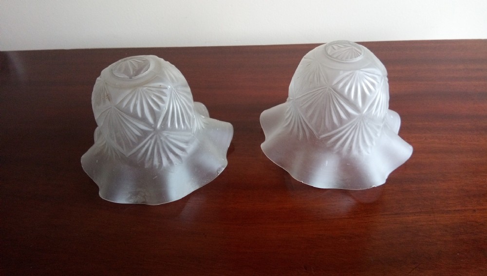 A pair of early 20th-century frosted glass lampshades featuring geometric fan motifs and frilled flared rims.