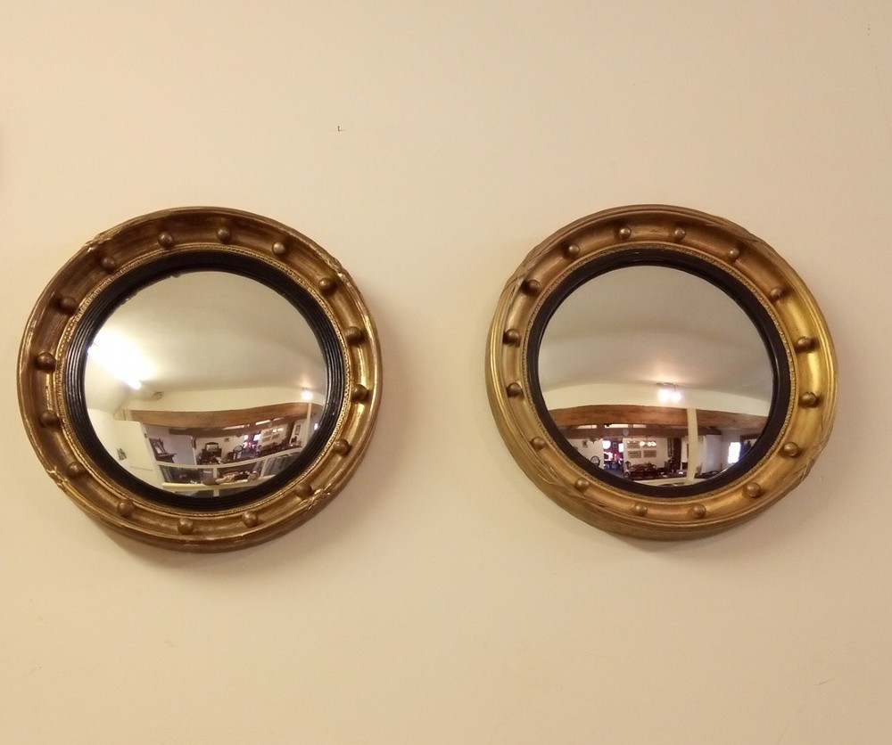 A near pair of Gilt convex mirrors from early 1900s in a Regency style.