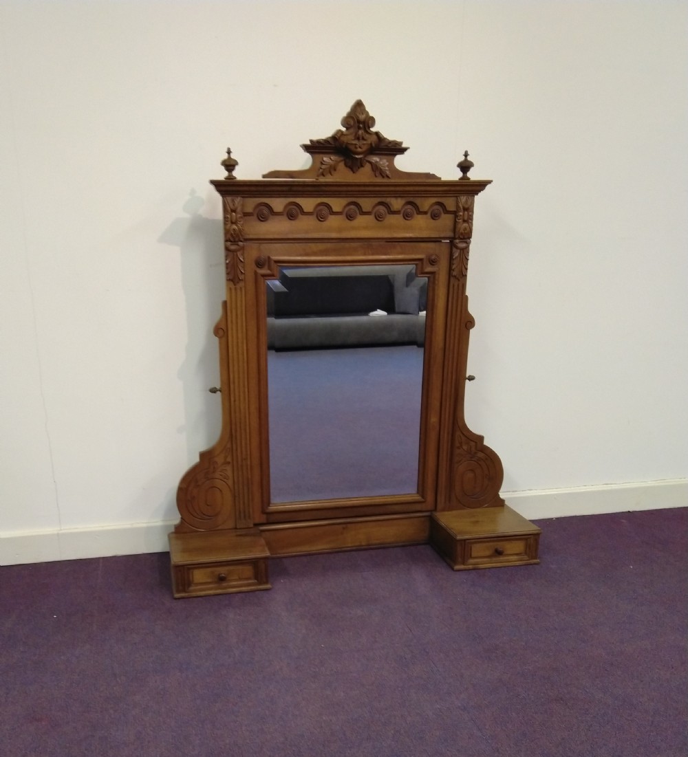 A carved French walnut dressing table mirror featuring an ornate carved pediment, fluted side columns, rectangular mirror glass, and two small trinket drawers at the base.