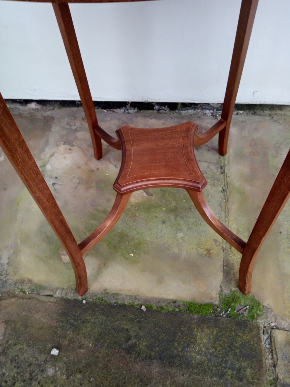 An Edwardian mahogany round occasional table featuring satinwood string inlay, slender splayed legs, and a small central undertier. View II