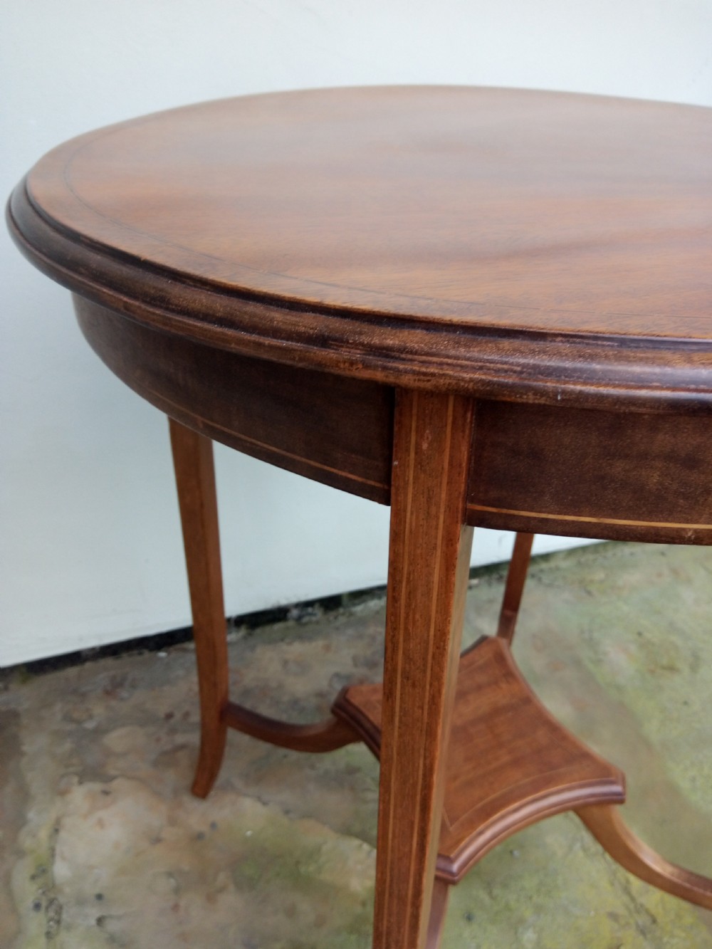 An Edwardian mahogany round occasional table featuring satinwood string inlay, slender splayed legs, and a small central undertier. View III