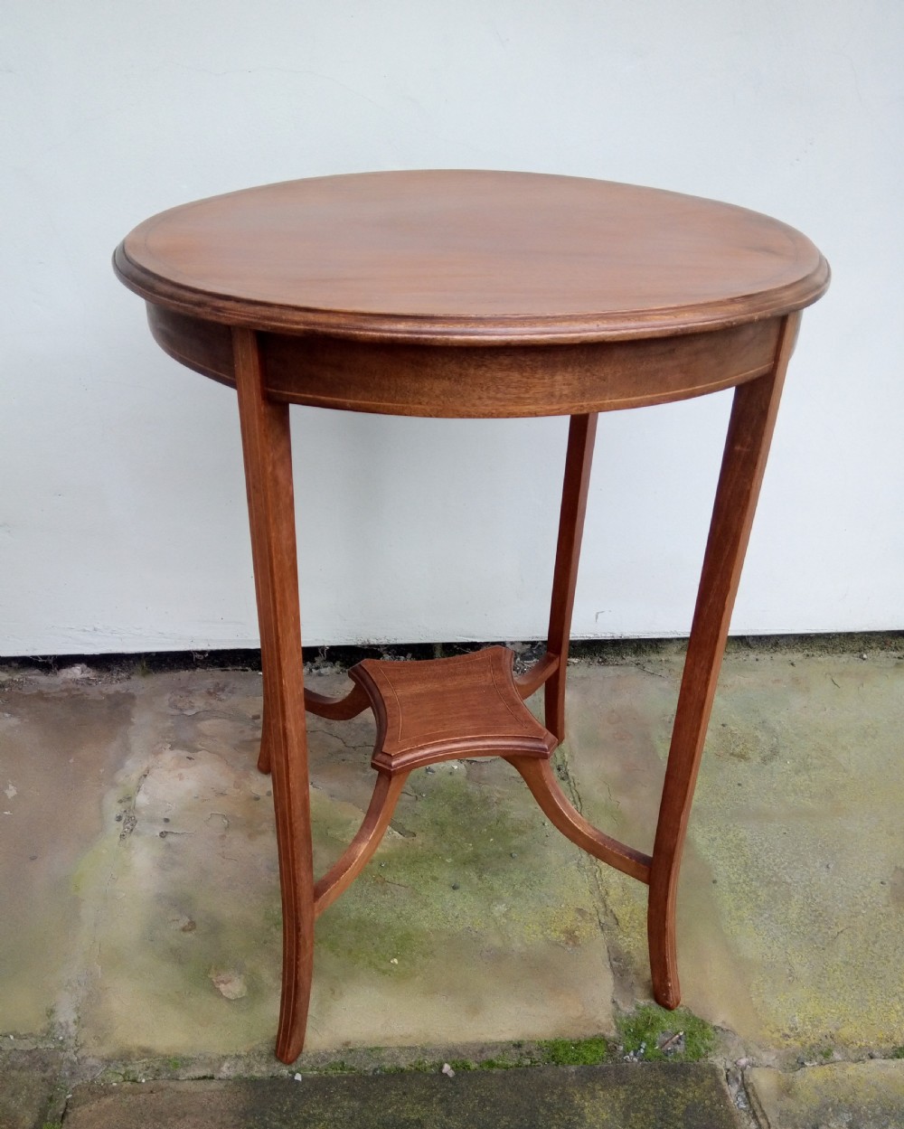 An Edwardian mahogany round occasional table featuring satinwood string inlay, slender splayed legs, and a small central undertier. View V