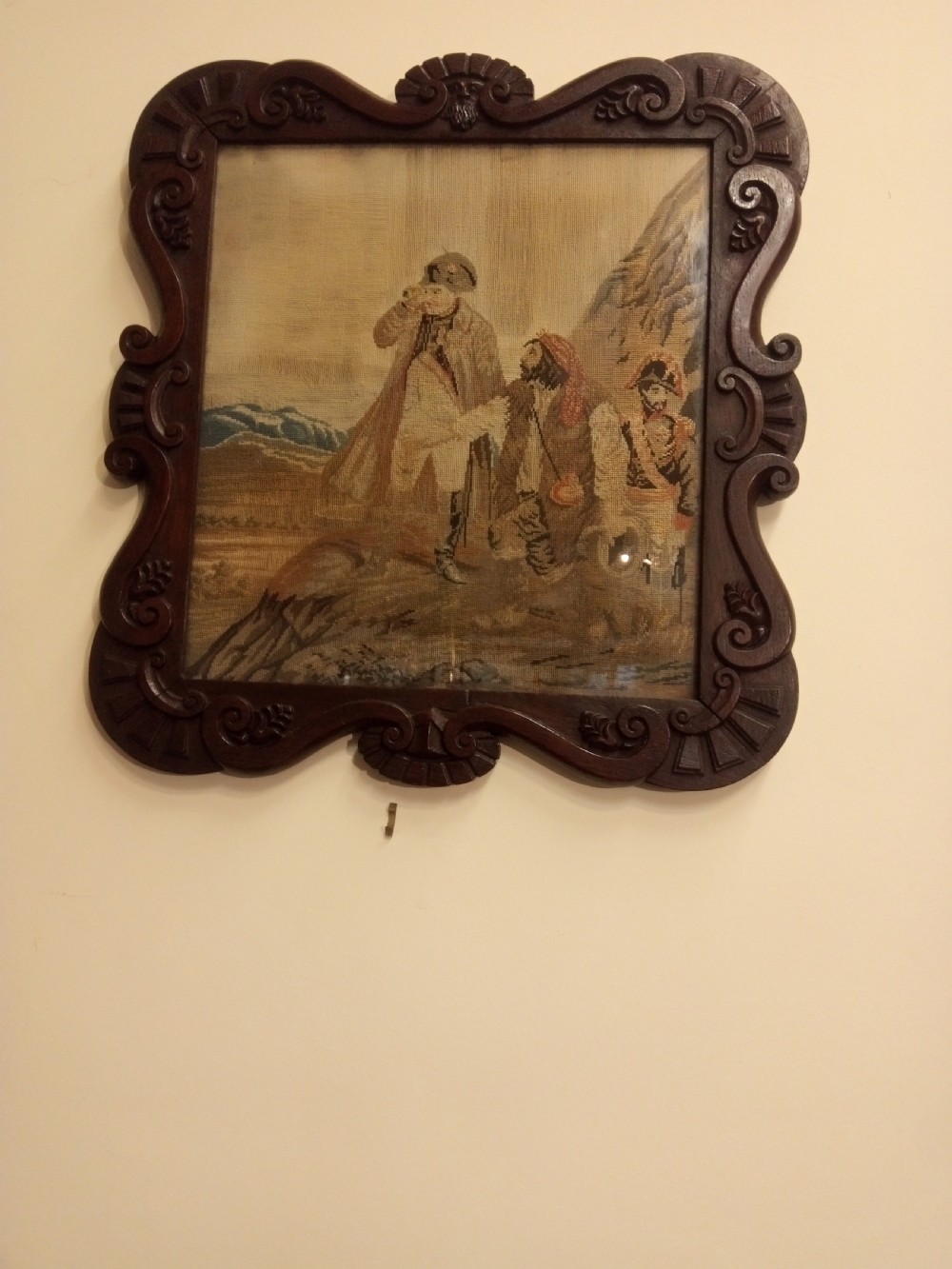A nineteenth-century wool needlework tapestry depicting historical figures in a landscape, set within a heavily carved dark oak frame with scrollwork. View VI