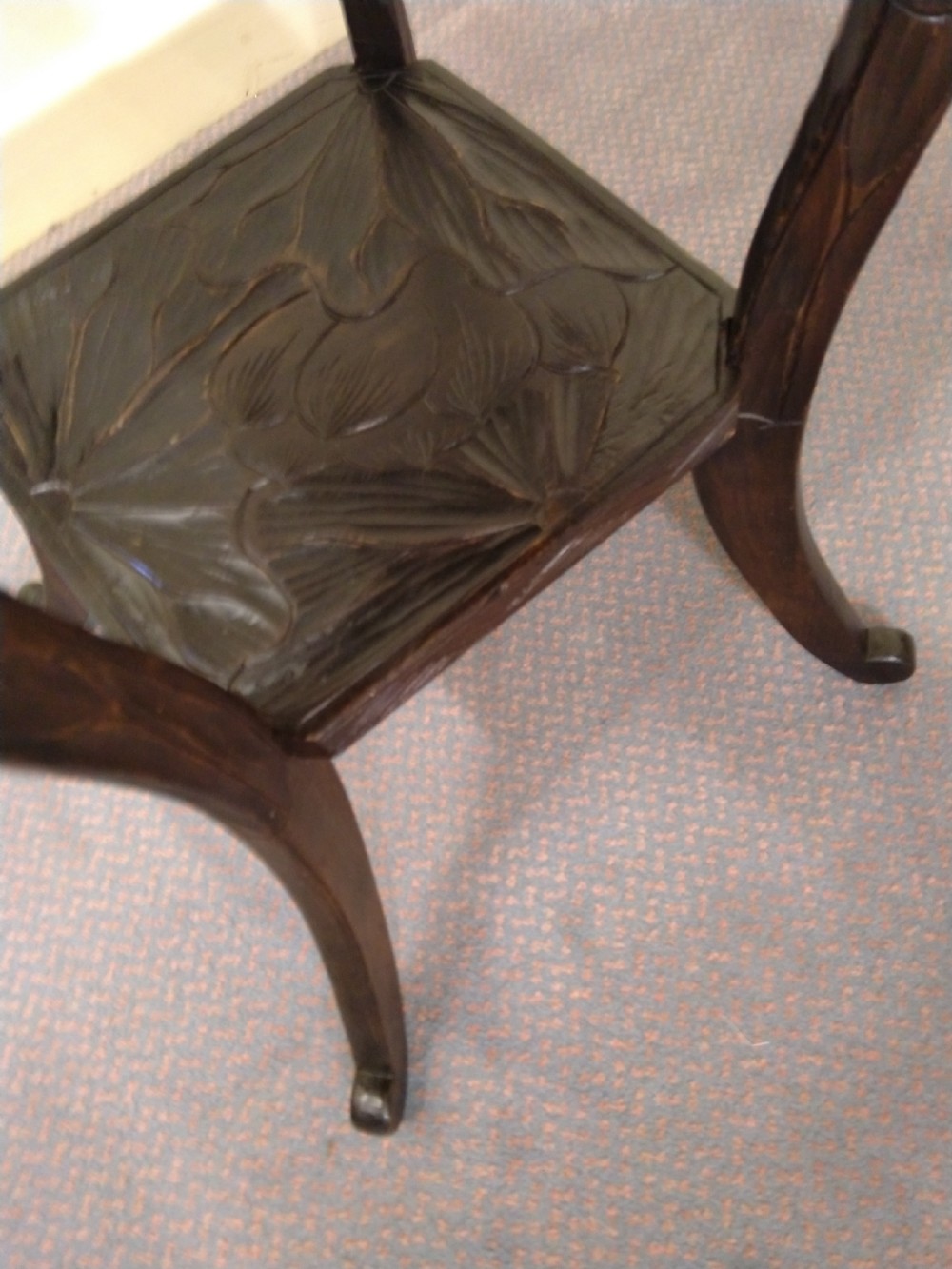 A dark brown carved wooden occasional table featuring relief botanical patterns on its square top surface and lower tier, supported by four curving legs. View IV