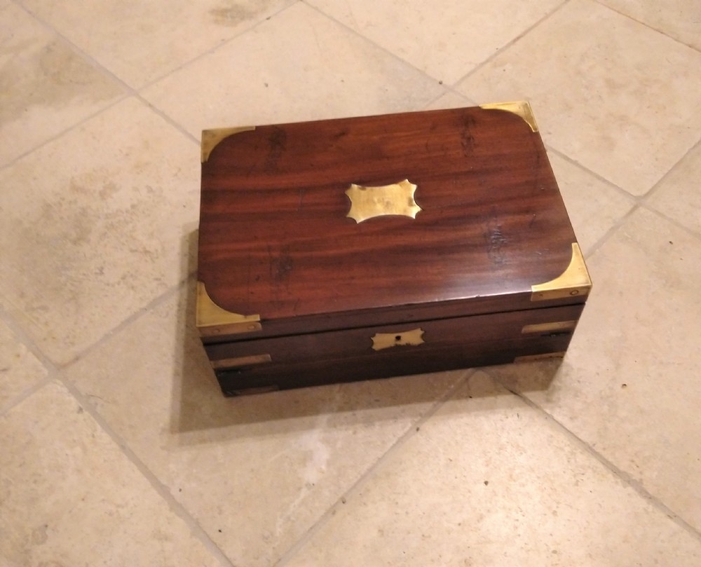 A rectangular dark mahogany wood writing slope featuring polished brass corner mounts, an escutcheon, and a brass central cartouche.