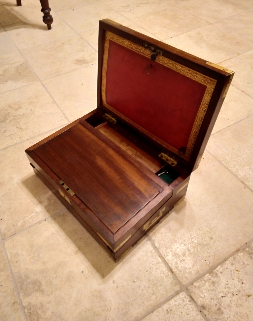 A rectangular dark mahogany wood writing slope featuring polished brass corner mounts, an escutcheon, and a brass central cartouche. View V