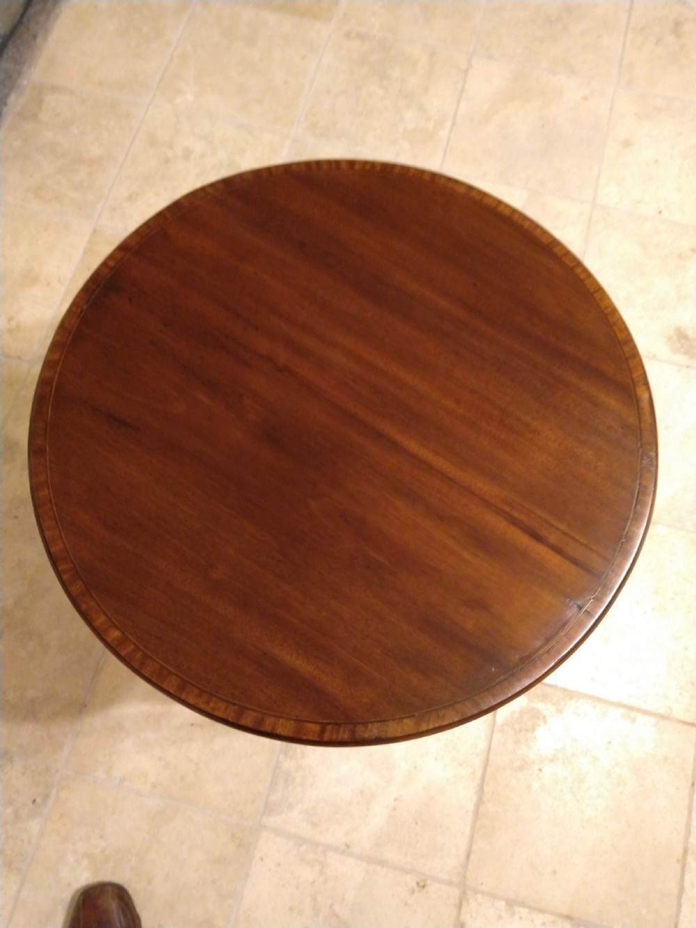 A circular early 20th-century mahogany occasional table featuring a decorative inlaid top border, slender curved legs, and a circular central undertier. View IV
