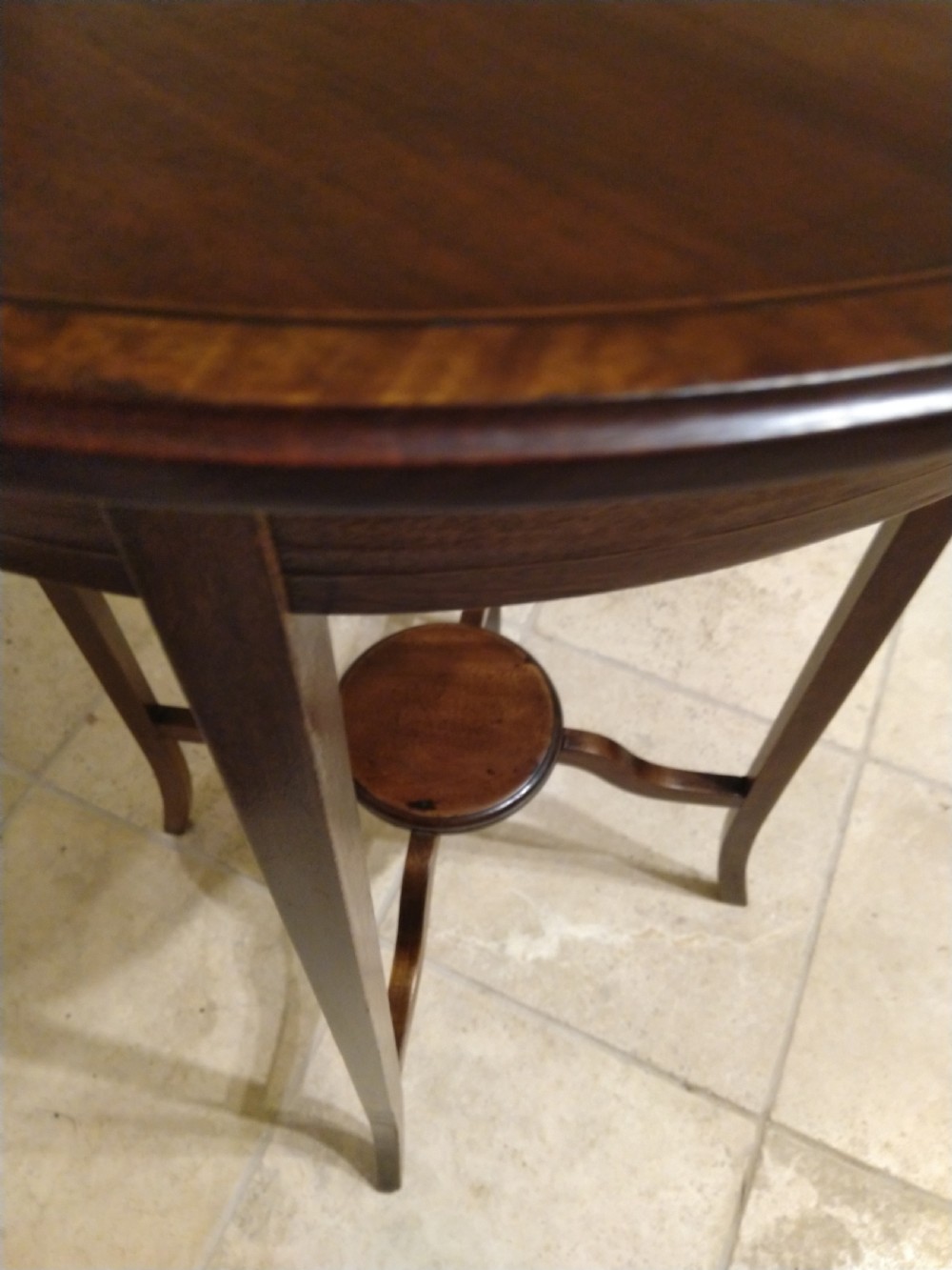 A circular early 20th-century mahogany occasional table featuring a decorative inlaid top border, slender curved legs, and a circular central undertier. View V