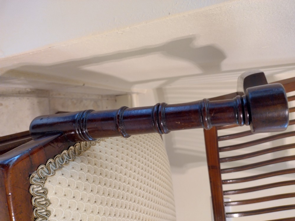 An Edwardian mahogany elbow chair featuring a vertical slat back with shell marquetry inlay, shaped arms, and a cream upholstered seat. View III