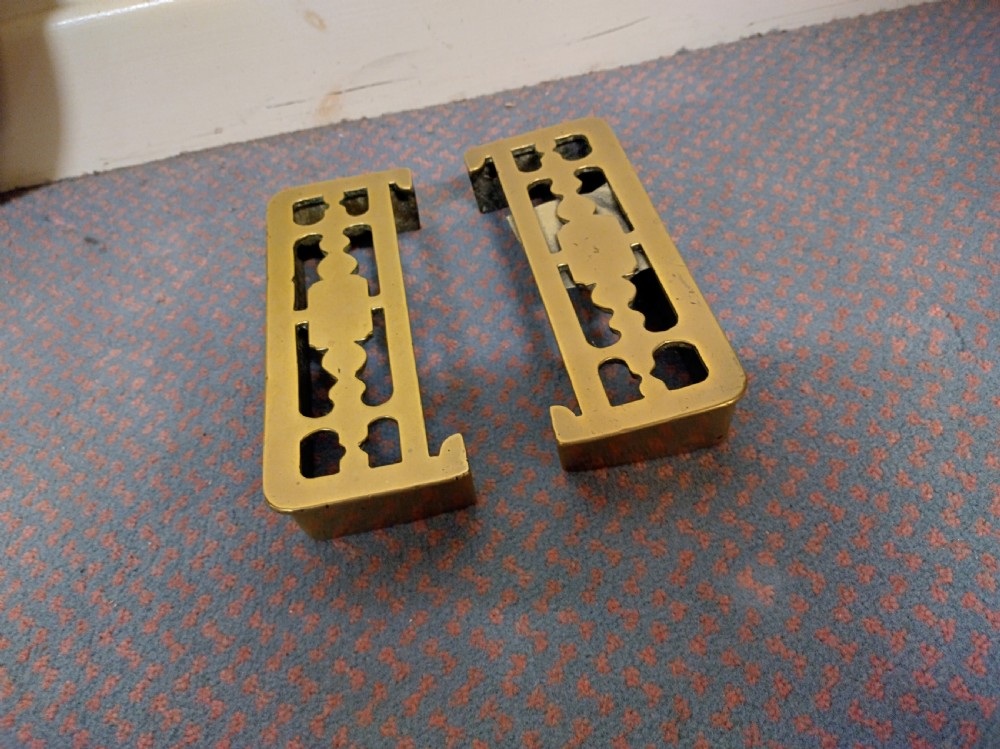 A pair of 19th-century rectangular cast brass fireplace trivets with pierced fretwork decoration and integrated fender mounting hooks.