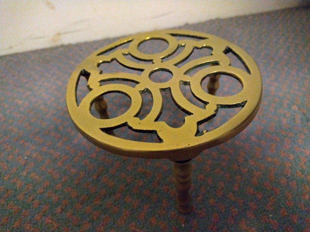 A pair of 19th-century rectangular cast brass fireplace trivets with pierced fretwork decoration and integrated fender mounting hooks. View V