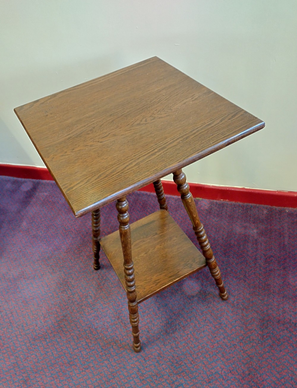 A square oak gypsy table featuring turned bobbin legs, a flat wooden top, and a lower square shelf.