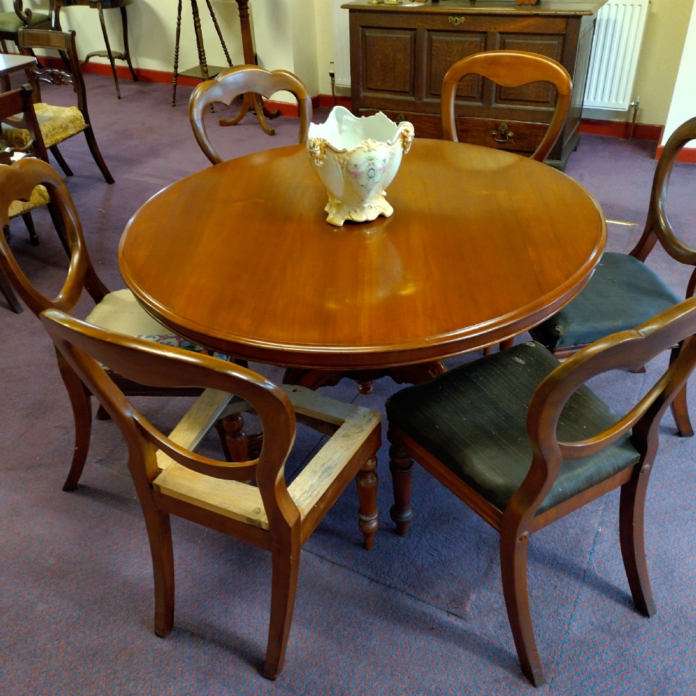 A 19th-century circular mahogany tilt-top pedestal table shown positioned vertically on splayed legs with castors. View II