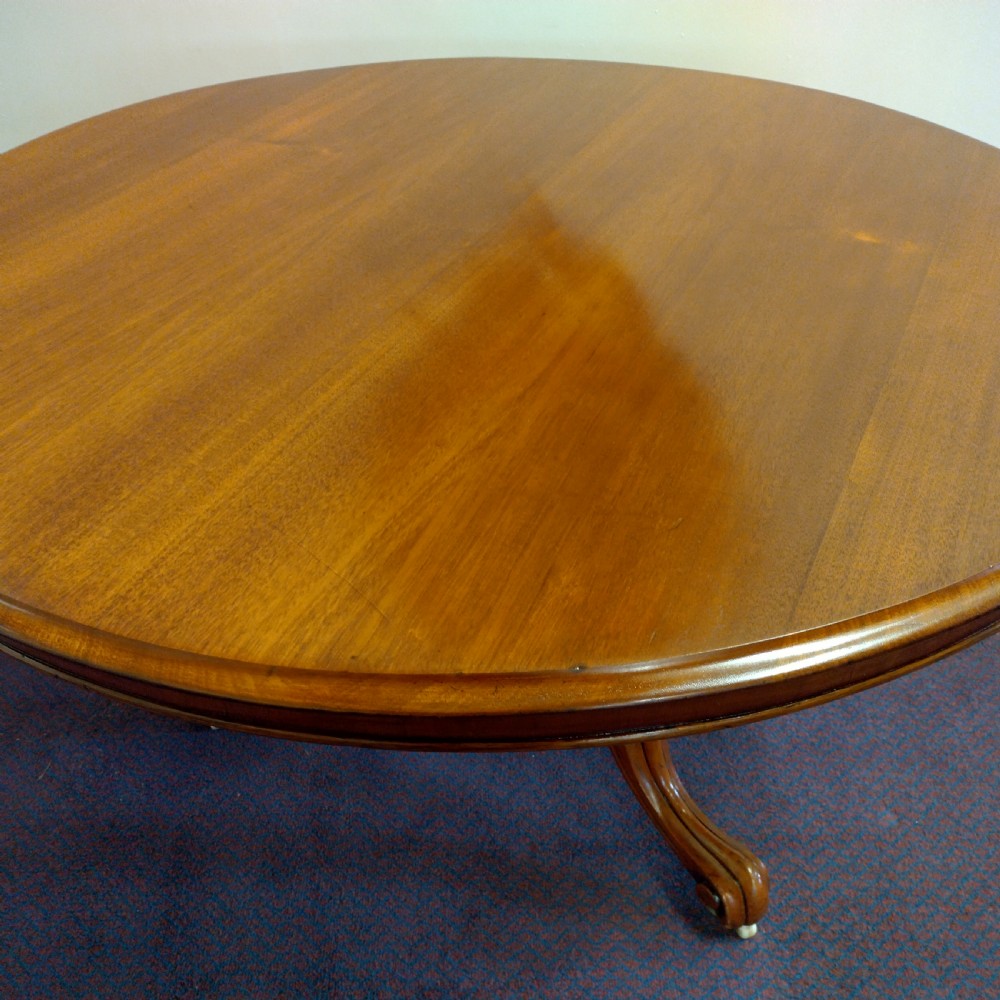 A 19th-century circular mahogany tilt-top pedestal table shown positioned vertically on splayed legs with castors. View IV