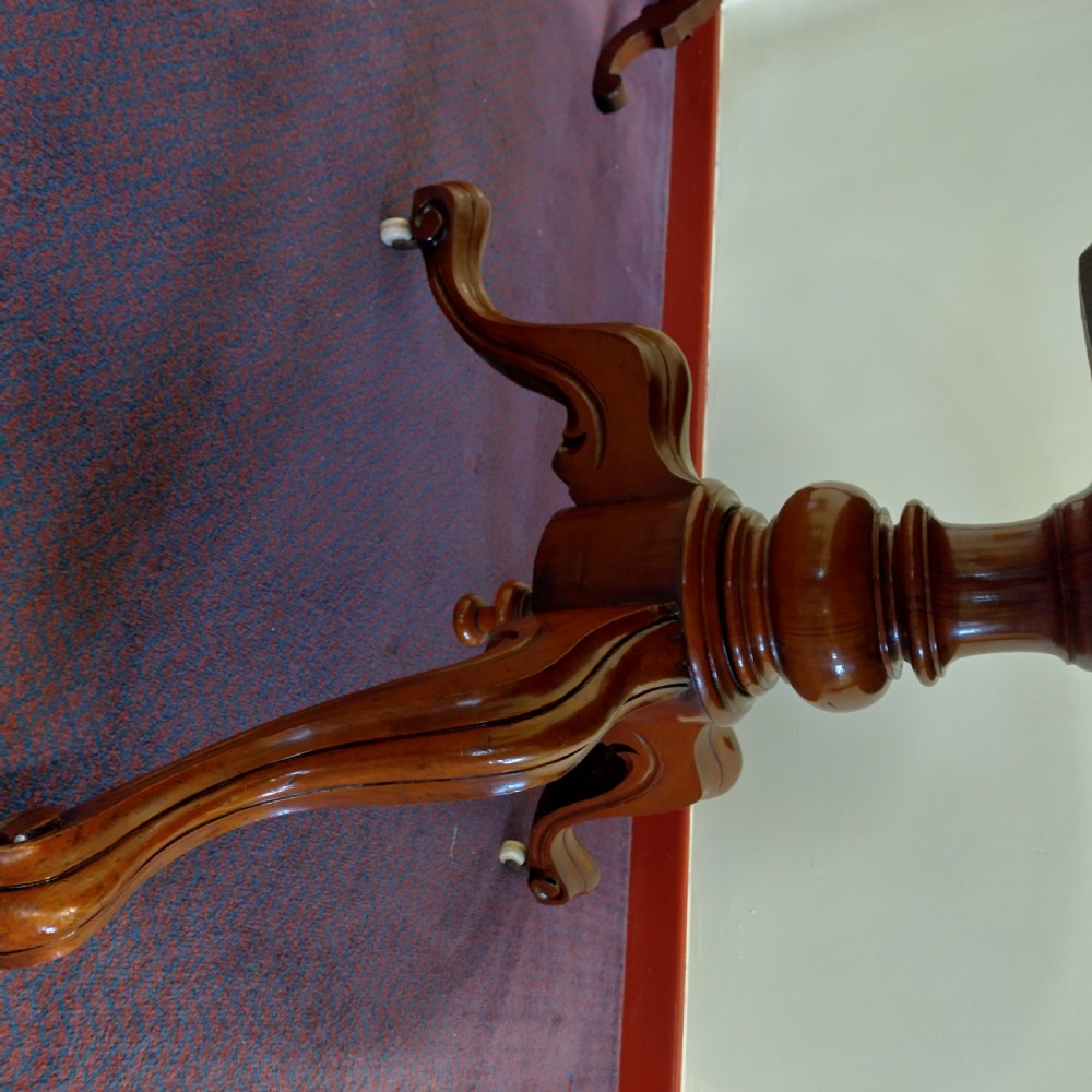 A 19th-century circular mahogany tilt-top pedestal table shown positioned vertically on splayed legs with castors. View V
