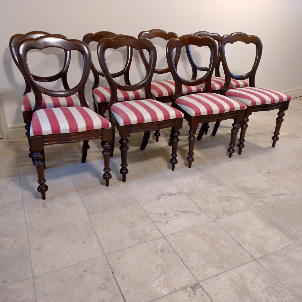 A set of eight 19th-century mahogany balloon back dining chairs with red and white striped upholstered seats and turned front legs.