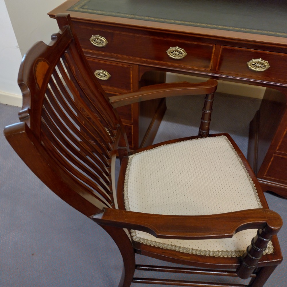 An Edwardian inlaid mahogany pedestal desk featuring twin pedestals with multiple drawers, brass oval drop handles, a dark leather writing insert, and a low gallery back with urn finials. View XI