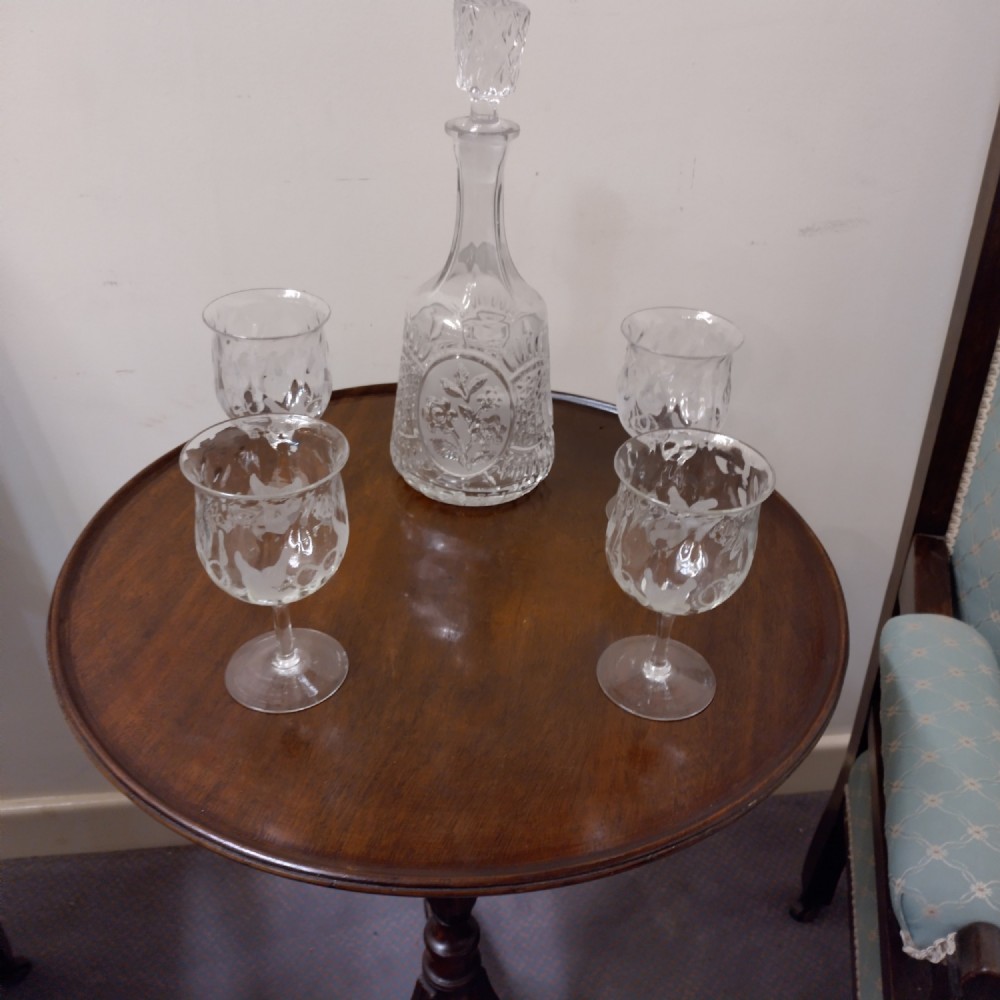 A clear etched glass decanter featuring a faceted stopper accompanied by four matching etched stemware glasses.