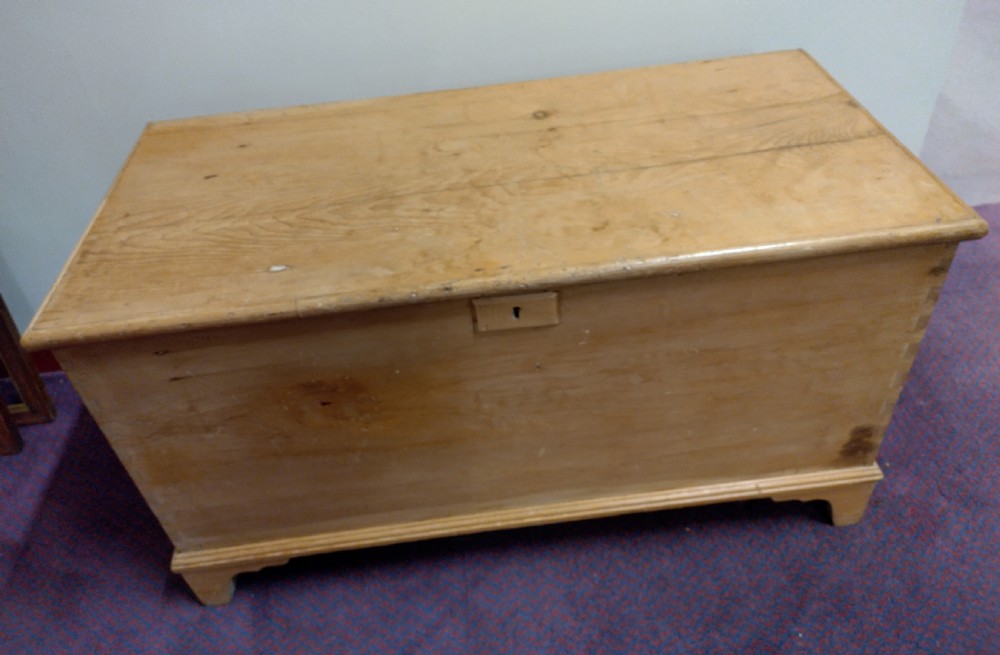 A nineteenth-century rectangular pine bedding chest with a hinged lid, brass keyhole escutcheon, and shaped bracket feet. View IV