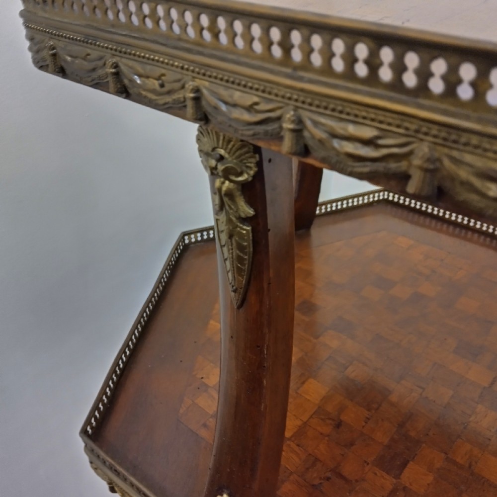 A hexagonal two-tiered French style occasional table featuring geometric wood parquetry inlay, pierced brass galleries, and cabriole legs with brass mounts. View II