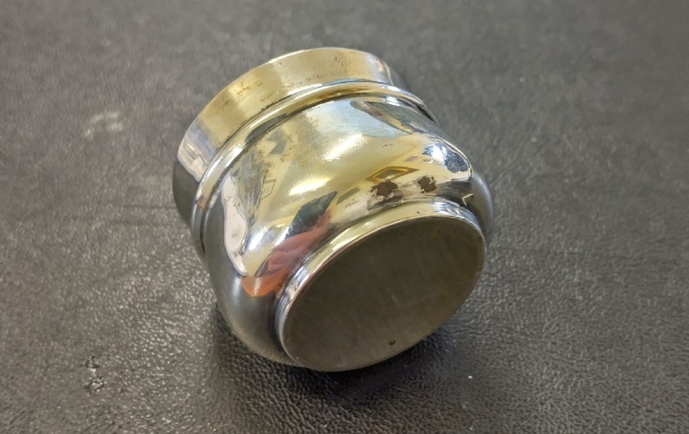 A circular sterling silver salt cellar with a cobalt blue glass liner insert and a silver salt spoon. View IV