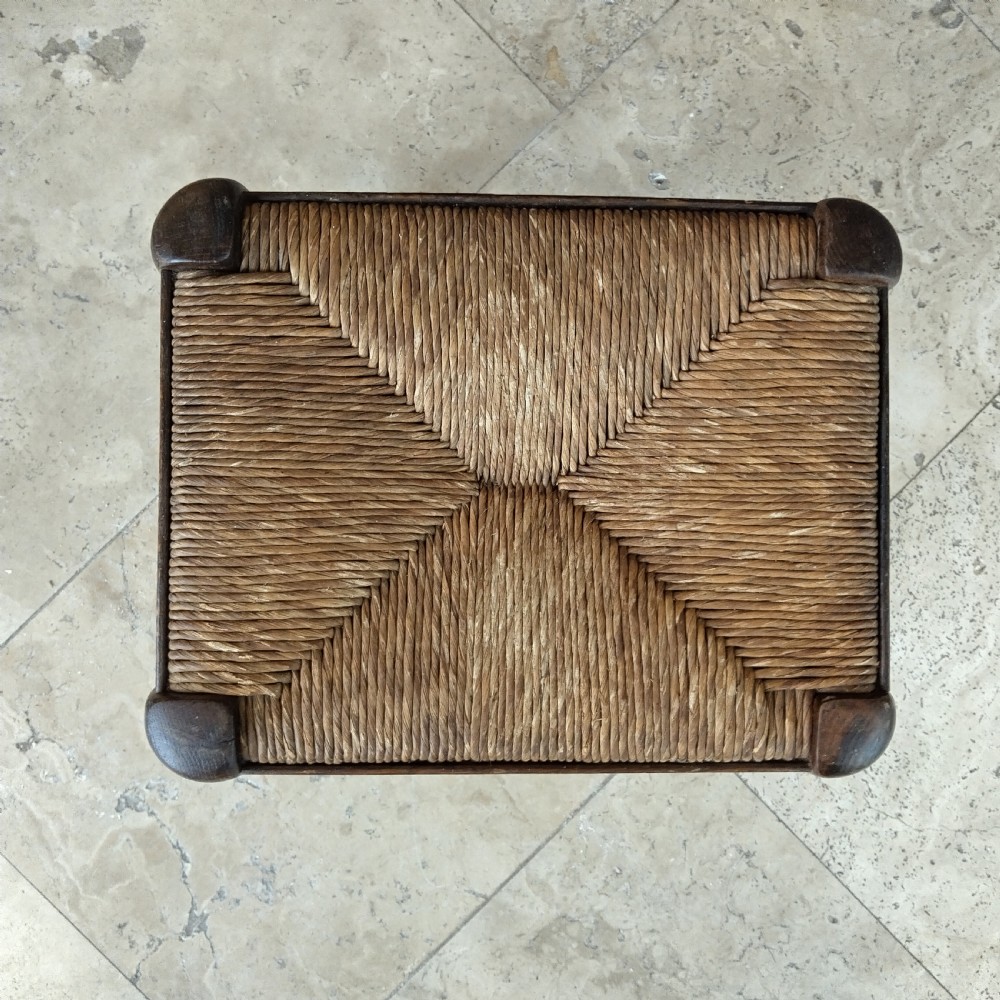 A compact rectangular dark oak stool featuring turned legs and a tightly woven natural rush seat. View II