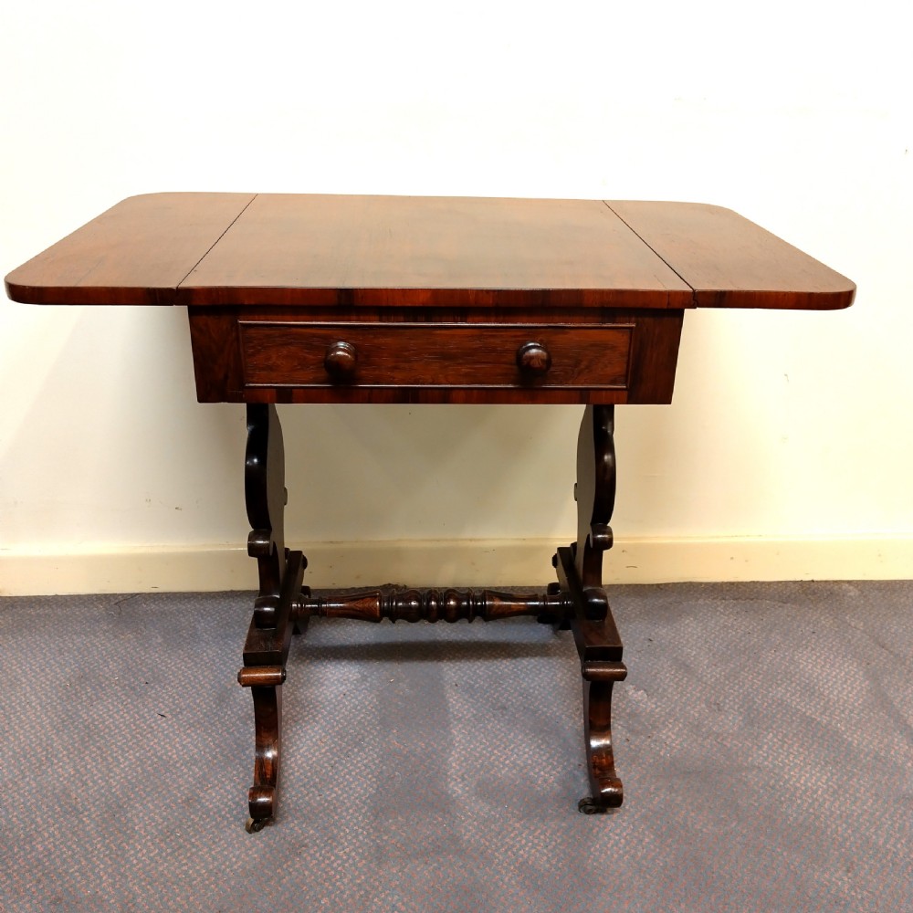 A 19th-century dark rosewood drop-leaf occasional table featuring a single drawer with wooden knobs, resting on curved trestle legs connected by a turned stretcher.
