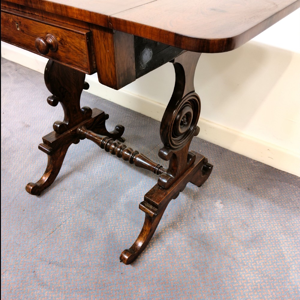 A 19th-century dark rosewood drop-leaf occasional table featuring a single drawer with wooden knobs, resting on curved trestle legs connected by a turned stretcher. View III