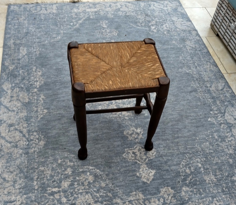A pair of dark country oak stools featuring woven natural rush seats and turned wooden legs. View II