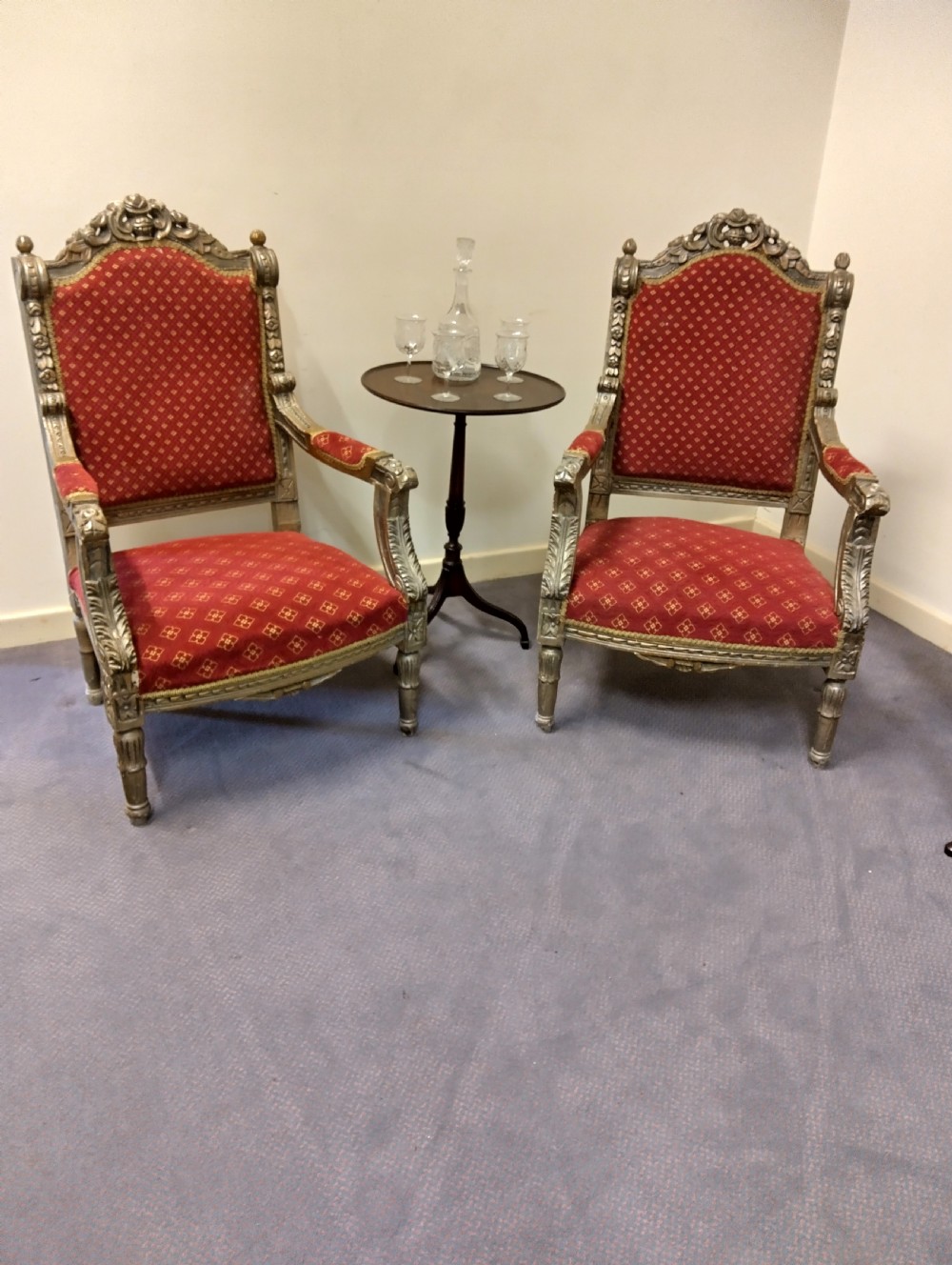 A pair of carved giltwood high-back armchairs upholstered in red patterned fabric with padded armrests and turned legs. View II