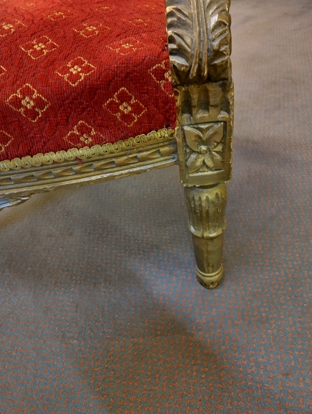 A pair of carved giltwood high-back armchairs upholstered in red patterned fabric with padded armrests and turned legs. View V