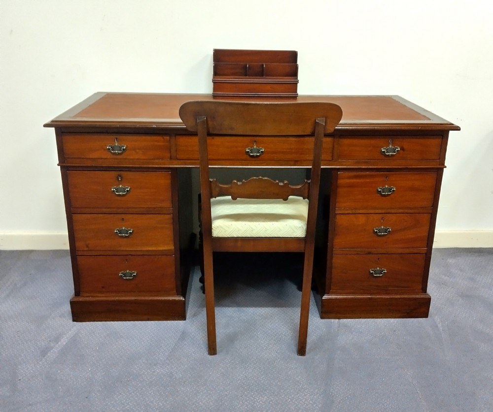 An Edwardian mahogany pedestal desk featuring a brown leather inset writing surface, nine drawers, and brass handles. View VII
