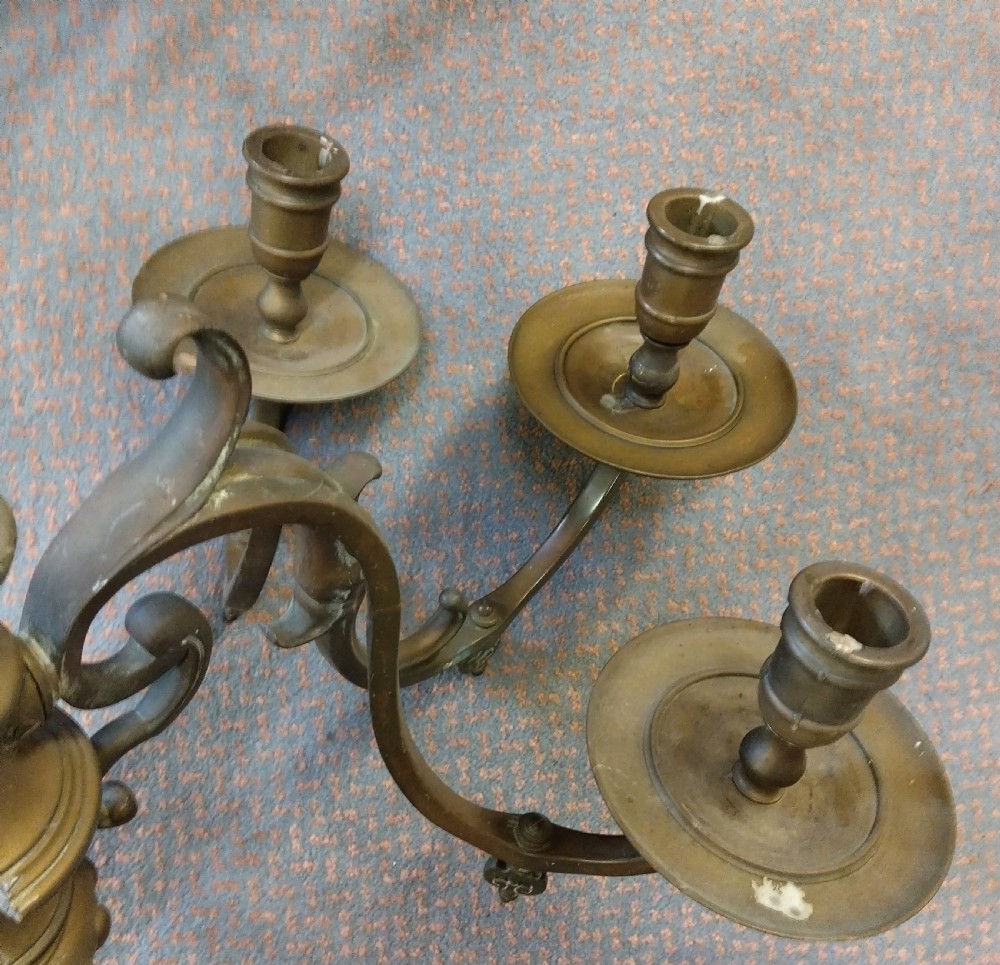 A pair of patinated three-arm solid brass wall sconces featuring fluted urn-shaped backplates and curved candle branches. View V