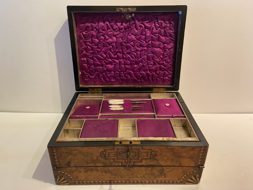 A 19th-century burr walnut box with geometric wood inlay borders, a central star medallion, and a metal key in the front keyhole. View II