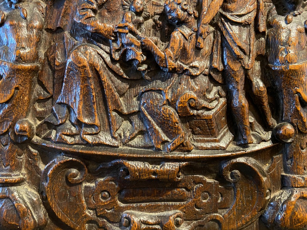 A 16th-century dark oak carved wood panel featuring a high-relief biblical scene enclosed within an arched frame supported by carved side columns. View IV