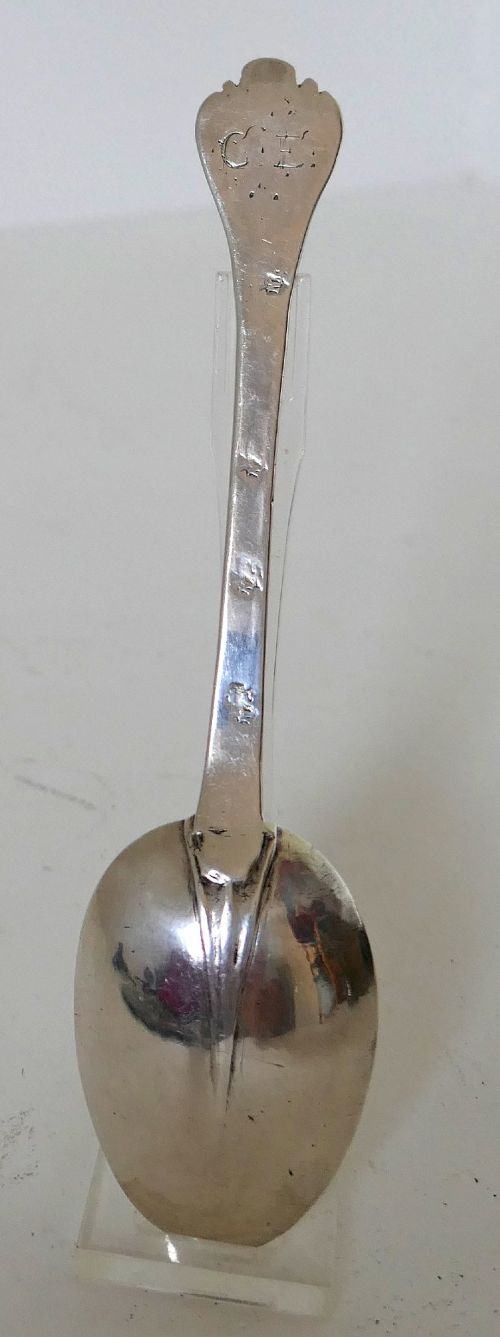 A 17th-century English sterling silver trefid spoon with a lobed terminal handle and an oval bowl displayed on a clear stand. View II