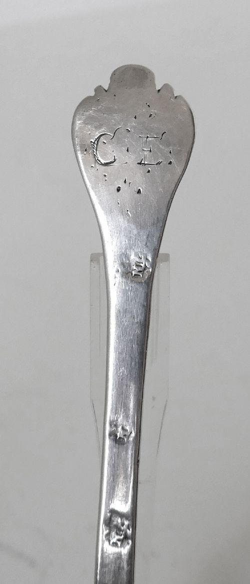 A 17th-century English sterling silver trefid spoon with a lobed terminal handle and an oval bowl displayed on a clear stand. View III