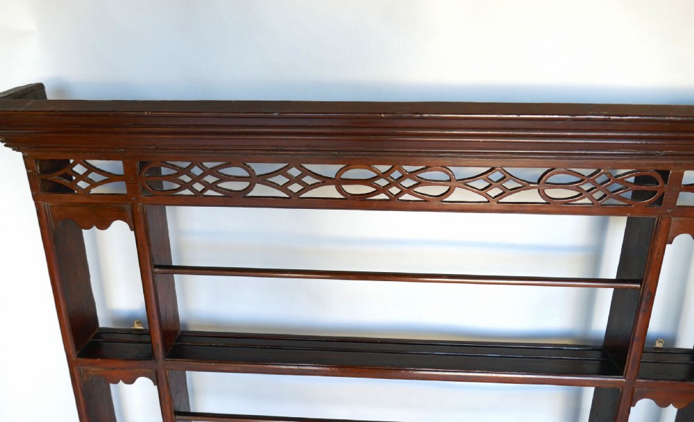 An 18th-century dark pine delft rack with a pierced fretwork frieze, a moulded cornice, three central plate shelves with retention bars, and open side alcoves. View III