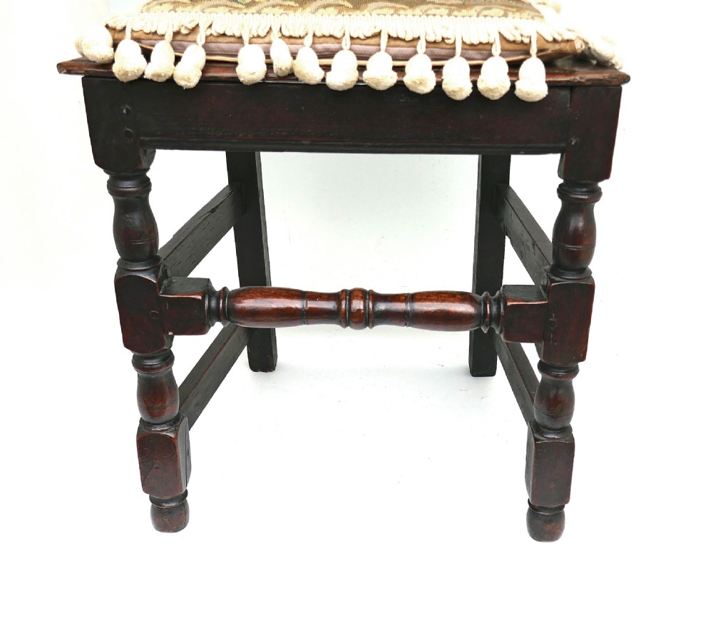 A late 17th-century dark oak side chair featuring a carved cresting rail, a pierced central splat back, turned legs, and a tapestry seat cushion with tassel fringe. View II