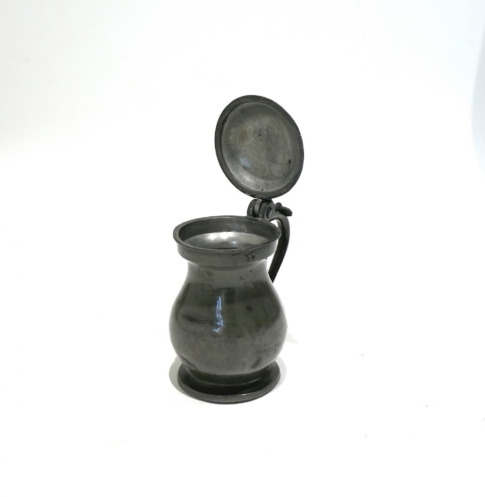 A 19th-century Scottish pewter half-pint lidded measure featuring a bulbous body, curved handle, thumbpiece, and stepped foot. View II