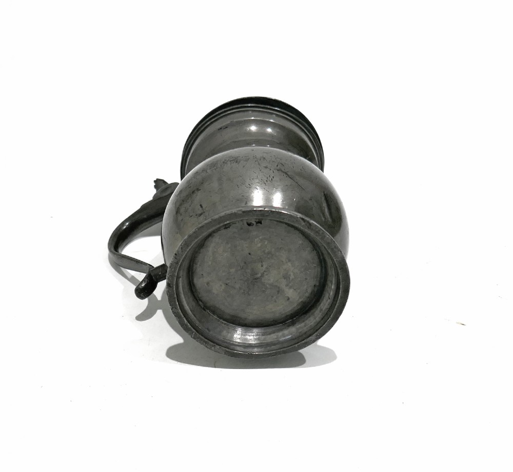 A 19th-century Scottish pewter half-pint lidded measure featuring a bulbous body, curved handle, thumbpiece, and stepped foot. View III